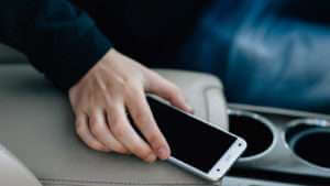 Person grabbing for their phone in the car. Phones are a constant distraction behind the wheel.